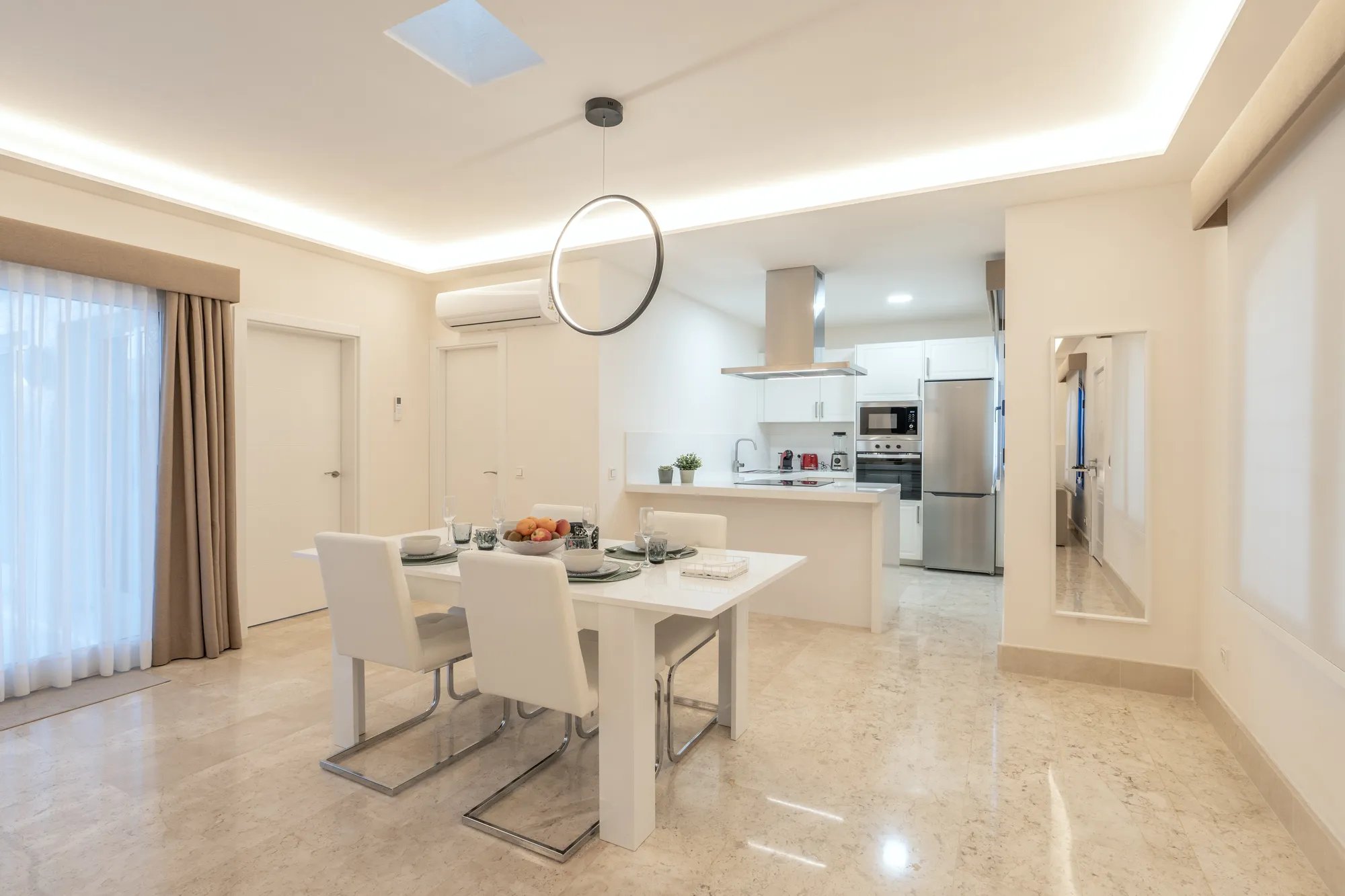 Comedor abierto con mesa preparada y cocina al fondo