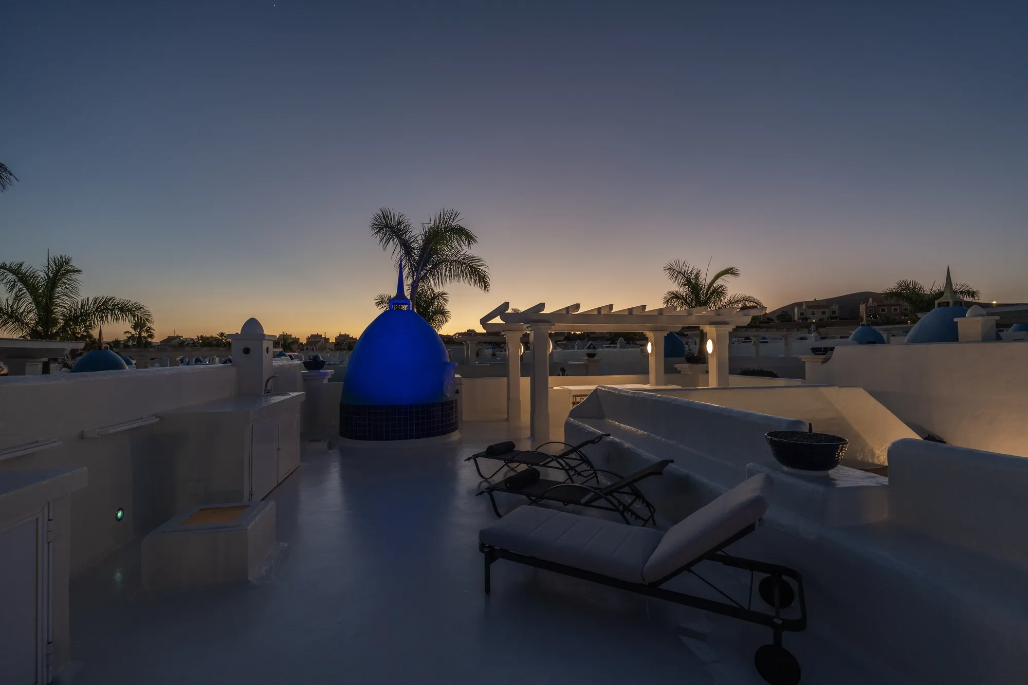 Azotea al atardecer con cielo naranja y cúpula azul